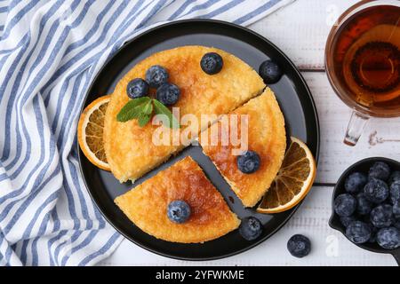 Deliziosa torta di semola con mirtilli e fette d'arancia su un tavolo di legno bianco, piatto Foto Stock
