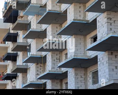 Costruzione di un nuovo edificio a più piani dall'esterno. Facciata e finestre di un nuovo edificio multi-appartamento. Vista dal basso verso l'alto Foto Stock