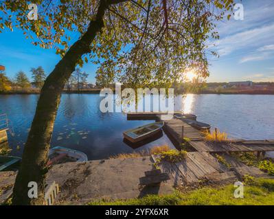 barche al molo sul fiume in autunno. Splendido paesaggio autunnale con laghetto d'acqua e tramonto Foto Stock