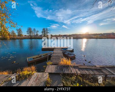 barche al molo sul fiume in autunno. Splendido paesaggio autunnale con laghetto d'acqua e tramonto Foto Stock