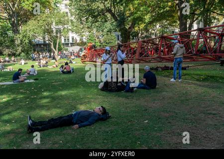 I visitatori del Madison Square Park apprezzano il clima caldo e instagionale accanto alla "Fixed Crane" di Nicole Eisenman, sul prato ovale, visto giovedì 31 ottobre 2024. Le temperature per i festeggiamenti di Halloween raggiunsero i 70 superiori (© Richard B. Levine) Foto Stock