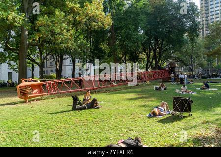 I visitatori del Madison Square Park possono godersi il clima caldo e instagionale che prende il sole accanto alla "gru fissa" di Nicole Eisenman, sul prato ovale, visto giovedì 31 ottobre 2024. Le temperature per i festeggiamenti di Halloween raggiunsero i 70 superiori (© Richard B. Levine) Foto Stock