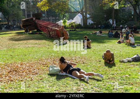 I visitatori del Madison Square Park possono godersi il clima caldo e instagionale che prende il sole accanto alla "gru fissa" di Nicole Eisenman, sul prato ovale, visto giovedì 31 ottobre 2024. Le temperature per i festeggiamenti di Halloween raggiunsero i 70 superiori (© Richard B. Levine) Foto Stock