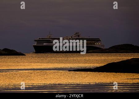 Linea di colori ibridi Symbolbild Fähre Color, Modernes Hybrid-Schiff, umweltfreundliche Technologie, leiser Betrieb, elegantes Dunkles Design, Leuchtender Schriftzug Color Line Hybrid , im Abendlicht auf dem Wasser, Goldene Reflexionen auf der Seeoberfläche, umgeben von Felsen, sanfte Beleuchtung an Bord, norwegische Fjordlandschaft, Ideal für Kurzstrecken, kombinierter Passagier- und Fahrzeugtransport geräuscharmer Foto Stock