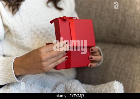 Ragazza irriconoscibile che apre una confezione regalo a Natale o San Valentino Foto Stock