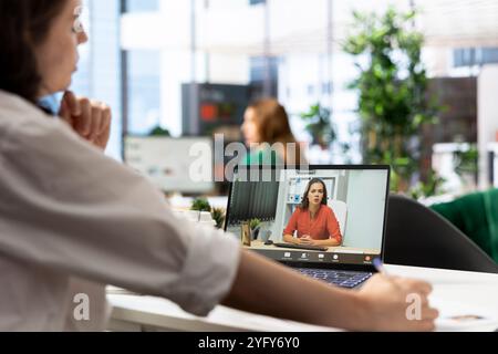 Il datore di lavoro conduce un colloquio con la persona in cerca di lavoro durante una chiamata a distanza sul laptop per determinare l'idoneità alla posizione aziendale. Dipendente delle risorse umane che esamina il curriculum durante la riunione di teleconferenza per verificare i criteri Foto Stock