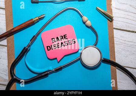 Stetoscopio e cartellino bianco con testo SULLE MALATTIE RARE su sfondo blu. Concetto medico. Foto Stock