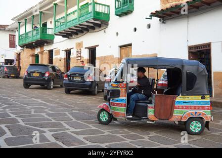 Guane, Santander, Colombia; 26 novembre 2022: Autista di taxi per moto seduto nel suo pittoresco veicolo colorato, in attesa che i turisti offrano un'attrazione turistica Foto Stock