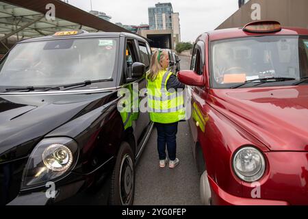 Londra, Regno Unito. 3 novembre 2024. Un volontario Poppy Cab si trova tra due taxi di Londra. Fondata quindici anni fa dai tassisti di Londra, Poppy Cabs offre viaggi gratuiti per i veterani militari che partecipano all'annuale Remembrance Day Service al Cenotaph di Westminster, Londra. Ispirati al Royal British LegionÃ-S Poppy Appeal, dove i distintivi di papavero rosso vengono scambiati con donazioni di beneficenza, questi tassisti si organizzano sotto l'iniziativa Ã¬Poppy CabsÃ®. Ogni anno, gli autisti offrono corse gratuite ai veterani dalle principali stazioni ferroviarie di Londra, per garantire che il loro soggiorno sia piacevole Foto Stock