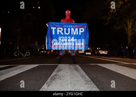 Una persona vestita da Spiderman tiene uno striscione con il testo “Trump 2024, Take America Back” in Black Lives Matter Plaza a Washington DC, USA martedì 5 novembre 2024. Foto Stock