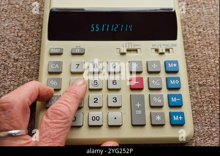 Dita premute sul tastierino di una calcolatrice Foto Stock