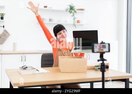 Il vlogger donna caucasico scopre eccitatamente il nuovo laptop digitale durante la registrazione video online in ufficio domestico. Una giovane donna condivide l'esperienza di unboxing con l'ingegno Foto Stock