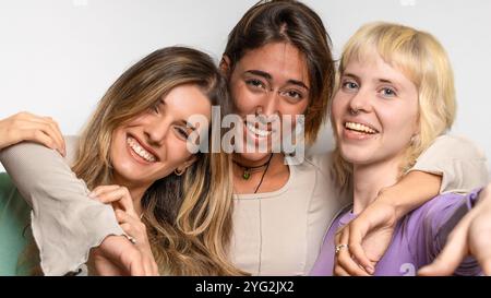 Primo piano ritratto di tre diversi giovani amici che sorridono e ridono con espressioni autentiche - momento di amicizia naturale - foto in studio Foto Stock