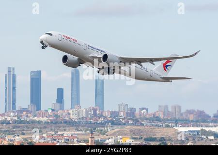 Aeroporto Barajas di Madrid. Airbus A350 aereo di linea della compagnia aerea China Eastern Airlines che decolla con la città di Madrid sullo sfondo. Foto Stock