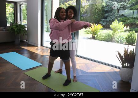 La donna sostiene il suo amico disabile mentre pratica yoga Foto Stock