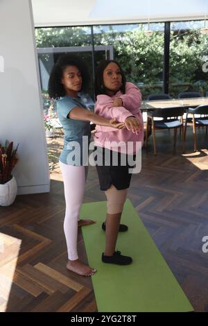 La donna sostiene il suo amico disabile mentre pratica yoga Foto Stock