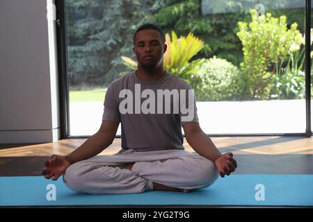 Uomo con sindrome di Down che medita in posizione di loto Foto Stock