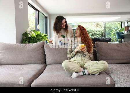 Due donne che ridono in salotto Foto Stock