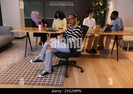 Donna d'affari di fiducia seduta davanti al tavolo in ufficio Foto Stock