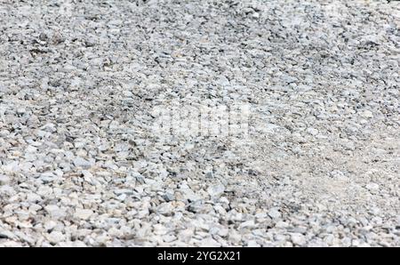 Ghiaia di grandi frazioni pietra frantumata costruzione aggregata struttura in pietra. La pietra schiacciata si trova a terra. Pietra di rottura. Struttura in ghiaia di granito Foto Stock