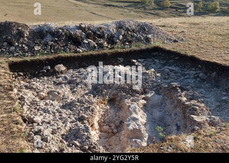 Fondo roccioso di una fossa archeologica scavata su una collina alla ricerca di manufatti storici. Lavori archeologici Foto Stock