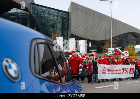 Monaco, Germania. 6 novembre 2024. I dipendenti BMW marciano dall'altra parte della strada di fronte allo stabilimento BMW durante uno sciopero di avvertimento. Mercoledì i dipendenti del settore metallurgico ed elettrico in Baviera continuano i loro avvertimenti. Il sindacato IG Metall ha annunciato una sospensione temporanea del lavoro per 74 imprese in Baviera. Crediti: Lennart Preiss/dpa/Alamy Live News Foto Stock