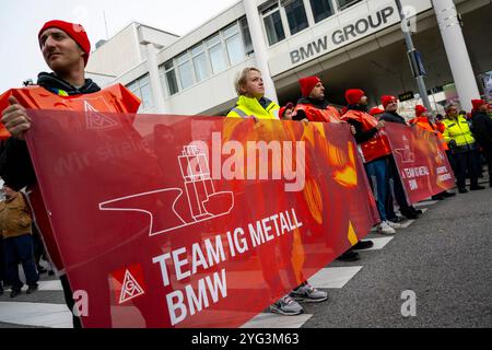 Monaco, Germania. 6 novembre 2024. I dipendenti BMW marciano dall'altra parte della strada di fronte allo stabilimento BMW durante uno sciopero di avvertimento. Mercoledì i dipendenti del settore metallurgico ed elettrico in Baviera continuano i loro avvertimenti. Il sindacato IG Metall ha annunciato una sospensione temporanea del lavoro per 74 imprese in Baviera. Crediti: Lennart Preiss/dpa/Alamy Live News Foto Stock