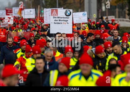 Monaco, Germania. 6 novembre 2024. I dipendenti BMW marciano dall'altra parte della strada di fronte allo stabilimento BMW durante uno sciopero di avvertimento. Mercoledì i dipendenti del settore metallurgico ed elettrico in Baviera continuano i loro avvertimenti. Il sindacato IG Metall ha annunciato una sospensione temporanea del lavoro per 74 imprese in Baviera. Crediti: Lennart Preiss/dpa/Alamy Live News Foto Stock