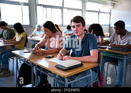 Ritrarre un giovane studente caucasico seduto alla scrivania con i compagni di classe in classe. Foto Stock