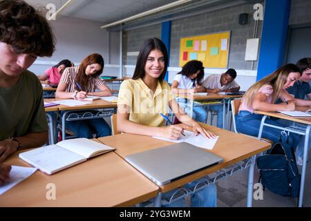 Ritratti felice giovane donna caucasica studentessa seduta alla scrivania con i compagni di classe in classe. Foto Stock