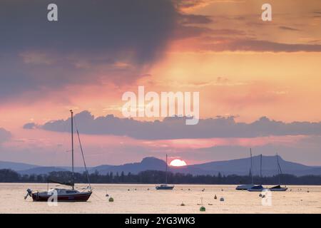 Tramonto su un lago con diverse barche a vela e nuvole scure, Seegarten, Allensbach, lago di Costanza, Baden-Wuerttemberg, Germania, Europa Foto Stock