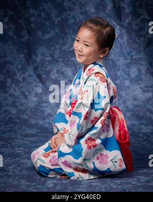 Ragazza nello yukata seduta in posizione eretta sul suo fianco e sorridente Foto Stock