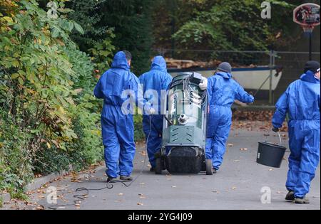 Hamm, Germania. 6 novembre 2024. I lavoratori in tuta portano una macchina per la pulizia in un sito. Dopo l'incendio in una torre di raffreddamento in un ex sito di miniera, sono stati trovati residui contenenti amianto nel quartiere. Esperti puliti e misurati, gli ospiti devono andare in un hotel per il momento. Crediti: Bernd Thissen/dpa/Alamy Live News Foto Stock