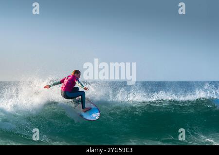 Una giovane surfista che cavalca un'onda al Fistral di Newquay, in Cornovaglia, nel Regno Unito, in Europa. Foto Stock