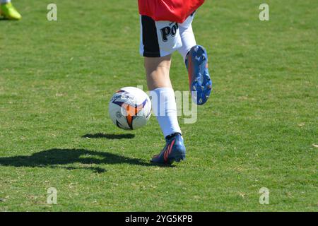 Giocatore di calcio giovanile che dribbla una palla su un campo soleggiato Foto Stock