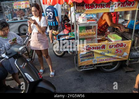 SAMUT PRAKAN, TAILANDIA, 16 GIUGNO 2024, la gente aspetta in un chiosco di strada che offre carne alla griglia, nel tardo pomeriggio Foto Stock