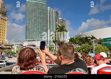 Miami, Florida, Stati Uniti - 1° dicembre 2023: Turisti che scattano foto con un telefono cellulare su un autobus turistico scoperto a due piani a Miami Foto Stock