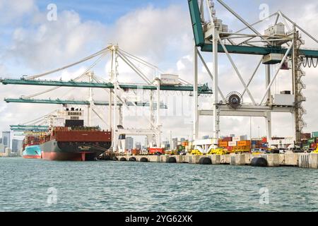 Miami, Florida, Stati Uniti - 1 dicembre 2023: Gru container nel porto di Miami con la nave container GSL Tripoli al molo Foto Stock