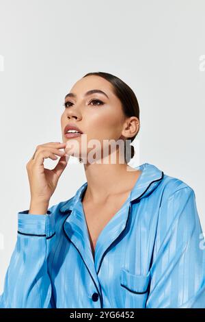 Una giovane donna con un comportamento aggraziato posa con cura in un abbigliamento da notte blu alla moda, dallo stile trasudo. Foto Stock