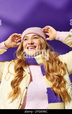 Una giovane donna allegra che indossa un caldo cappello e sciarpa, crogiolandosi alla luce del sole e sorridente. Foto Stock