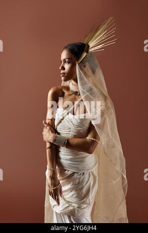 Una splendida donna afro-americana indossa elegantemente un abito bianco, che irradia grazia con una collana di perle. Foto Stock