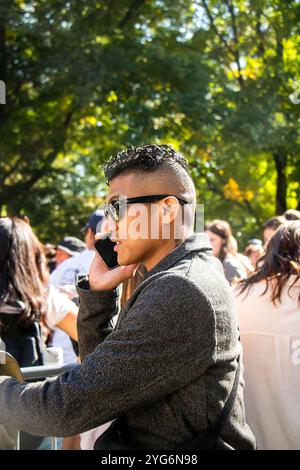 Profilo laterale di un giovane uomo asiatico o ispanico dalla testa rasata con occhiali rayban a manhattan New york, USA, che parla al cellulare Foto Stock