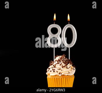 Numero 80 candele sagomate - cupcake di compleanno su sfondo nero. Foto Stock