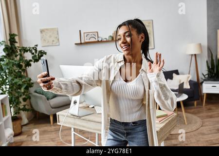 Una giovane donna allegra studia a casa e ama connettersi con gli altri tramite videochiamata. Foto Stock