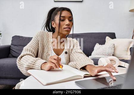 Impegnata nell'apprendimento a distanza, una donna si concentra sui suoi studi dal suo comodo salotto. Foto Stock