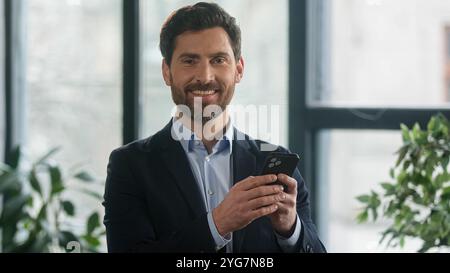 Uomo caucasico guardare fotocamera telefono di successo uomo d'affari maturo imprenditore leader datore di lavoro professionale manager indoor uomo d'affari ritratto Foto Stock