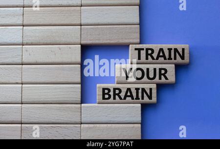 Allena il simbolo del cervello. Parole concettuali allenate il vostro cervello su blocchi di legno. Splendido sfondo viola. Mano d'affari. Affari e formazione del cervello Foto Stock