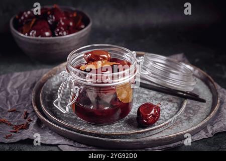 Prugne marinate con spezie in vaso di vetro sul tavolo da cucina Foto Stock