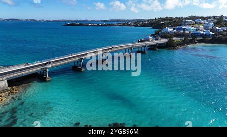 Un dinamico drone che cattura Waterford Bridge attraverso le splendide acque bermudane, creando schizzi e sentieri nel mare turchese cristallino Foto Stock