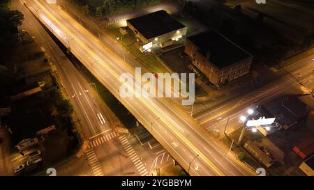 Gli scatti notturni a lunga esposizione del paesaggio urbano catturano vivaci percorsi di luce dalle auto di passaggio e dalle strade illuminate. Foto Stock